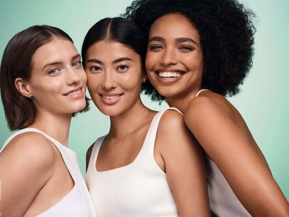 Trois femmes souriantes vêtues d'un haut blanc